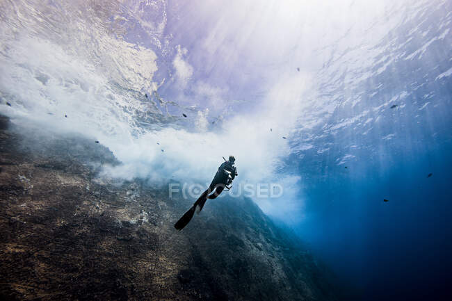 Vista submarina de buzo femenino explorando roca partida pinnacle, Socorro, Baja California, México - foto de stock
