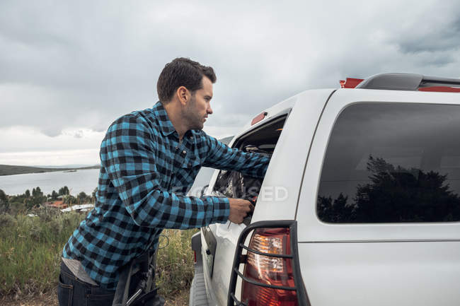 Mid adult man reaching into window of parked car, Silverthorne, Colorado, USA — Stock Photo