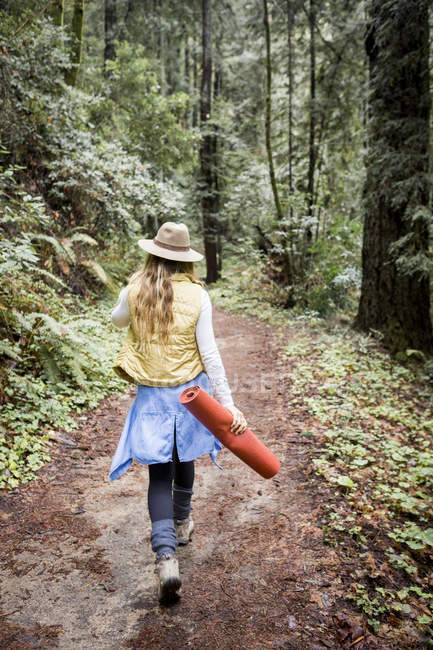 Jeune femme en trilby flânant dans la forêt — Photo de stock