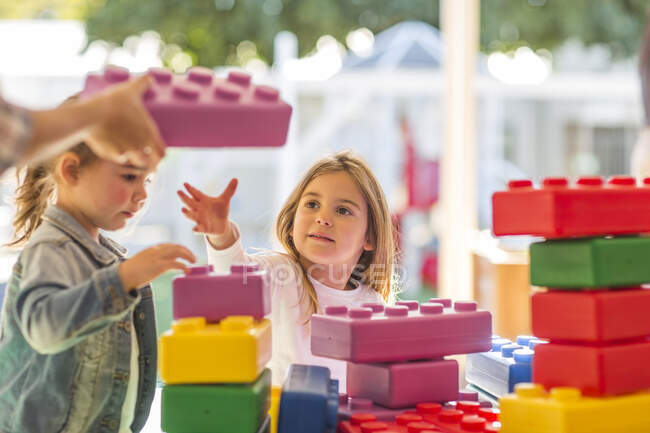 Dos niños pequeños, al aire libre, jugando con bloques de espuma - foto de stock