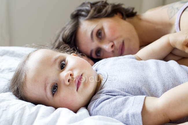 Retrato de mãe e bebê filha relaxando na cama — Fotografia de Stock