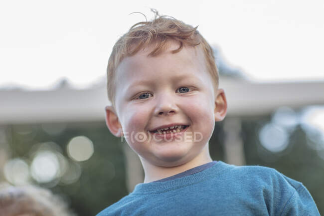 Niño pelirrojo en preescolar, retrato en el jardín - foto de stock