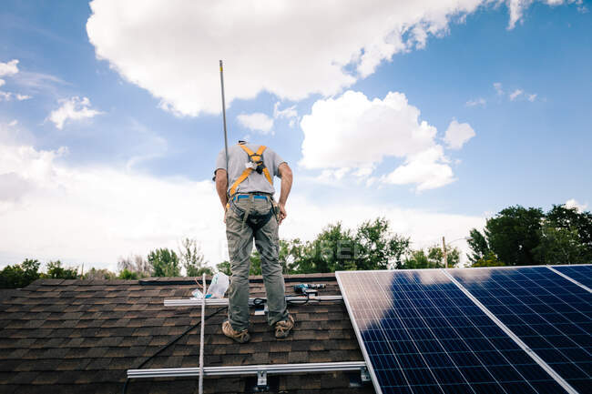 Workman instalación de paneles solares en el techo de la casa, vista trasera - foto de stock