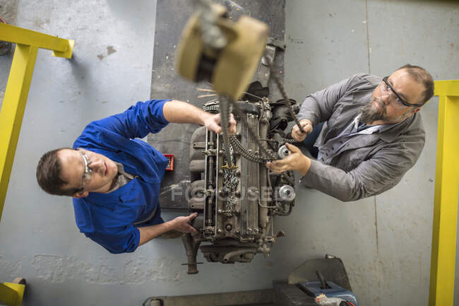 Overhead view of  car mechanics hoisting car engine in repair garage — Stock Photo