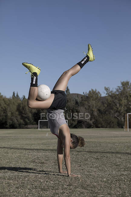 Mulheres em campo de futebol fazendo handstand com futebol — Fotografia de Stock