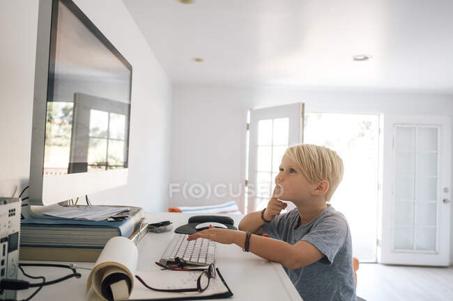 Запутавшийся мальчик смотрит на экран компьютера — стоковое фото