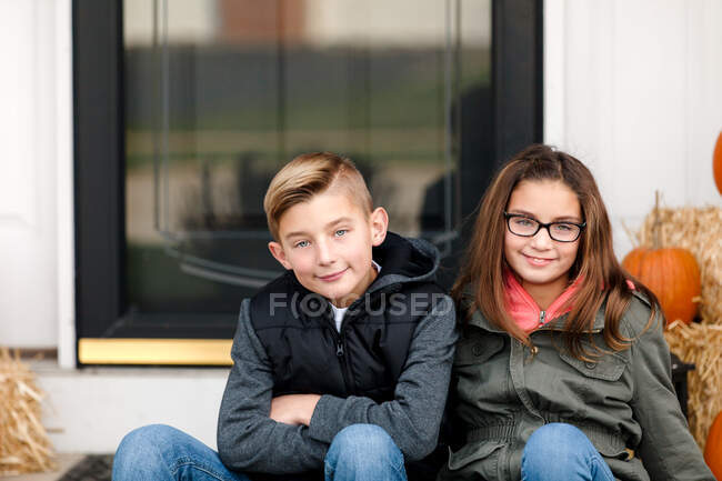 Retrato de niño y hermana gemela en el porche delantero - foto de stock