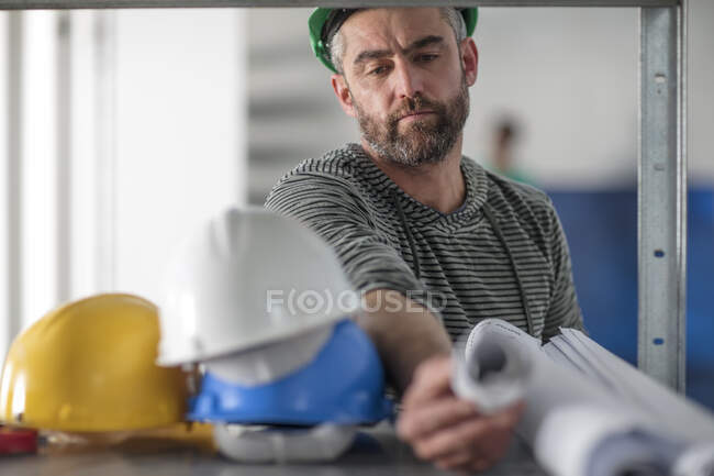 Man with blueprints and hard hats — Stock Photo