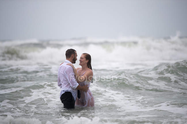 Влажная романтическая пара в объятиях в море — стоковое фото