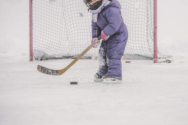 Молода дівчина грає в хокей, готуючись вдарити шайбу, середня секція — стокове фото