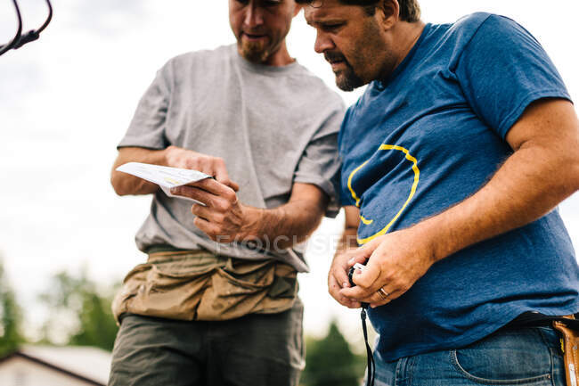 Two workmen outdoors, looking at document, low angle view — Stock Photo