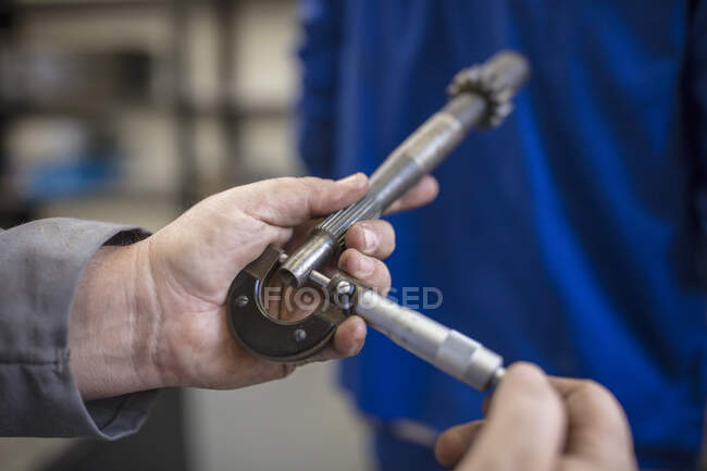 Manos del mecánico masculino del coche que sostiene la pieza del coche en el garaje de la reparación - foto de stock