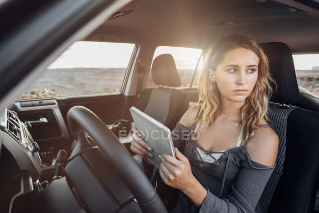 Молода жінка в автомобілі тримає цифровий планшет, мексиканські капелюхом, Юта, США — стокове фото
