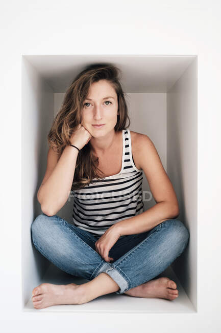 Portrait de jeune femme assise dans une boîte — Photo de stock