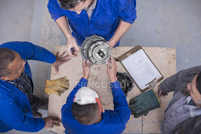 Overhead view of car mechanic team inspecting car part in repair garage — Stock Photo
