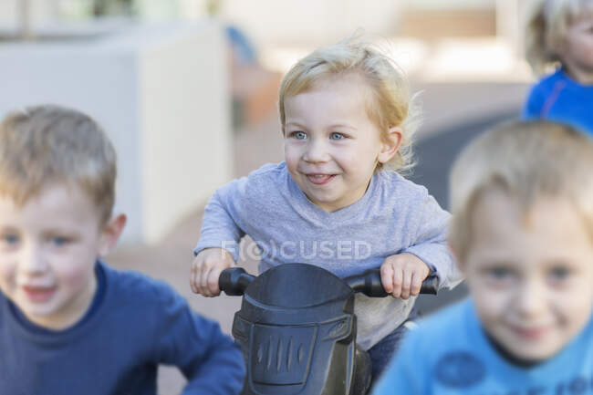 Хлопчики на дошкільних гонках штовхають мотоцикли в саду — стокове фото