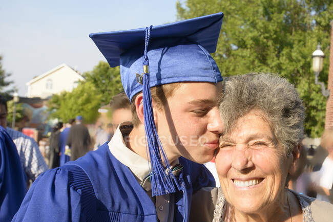 Adolescent garçon embrasser grand-mère à la cérémonie de remise des diplômes — Photo de stock