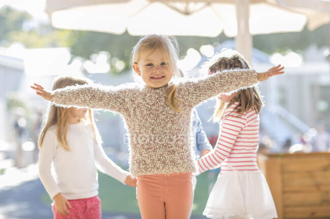 Portrait of young girl, arms outstretched, smiling — Stock Photo
