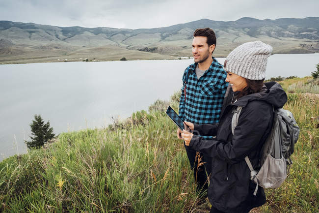 Coppia escursioni, in piedi accanto a Dillon Reservoir, giovane donna in possesso di tablet digitale, Silverthorne, Colorado, Stati Uniti d'America — Foto stock