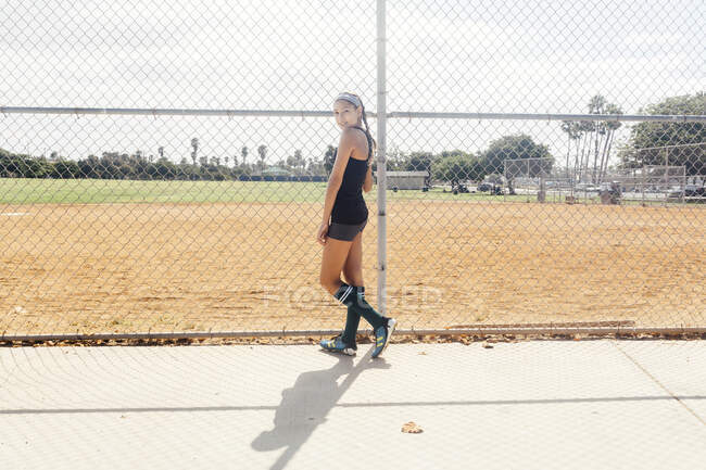 Portrait of schoolgirl soccer player at wire fence on school sports field — Stock Photo
