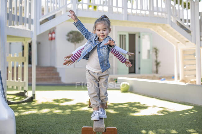 Girls at preschool, portrait balancing on balance beam in garden — Stock Photo