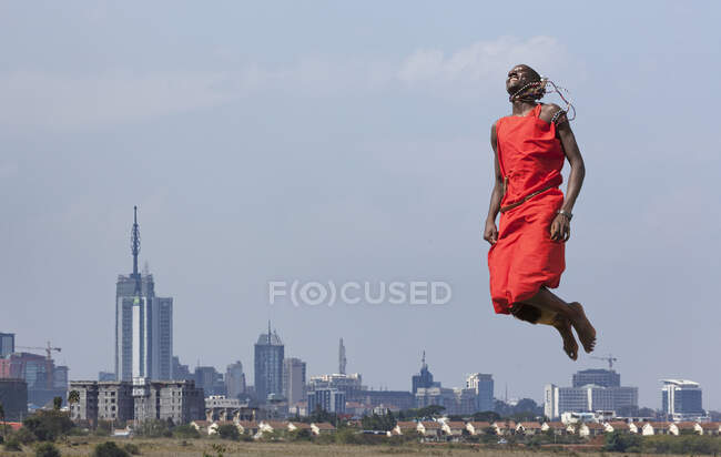 Masai guerrero saltando en el aire durante la danza tradicional, Nairobi, Kenia, África - foto de stock