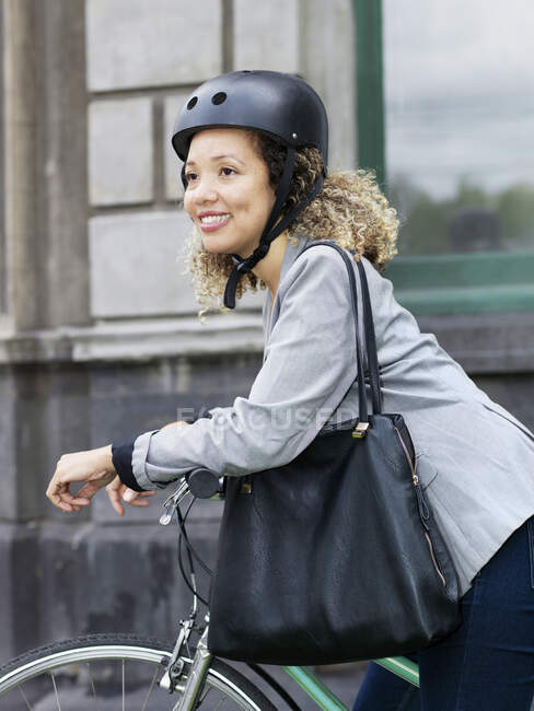 Mulher adulta média sentada na bicicleta, usando capacete de segurança — Fotografia de Stock