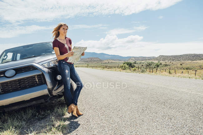 Mujer con mapa apoyado en el coche - foto de stock