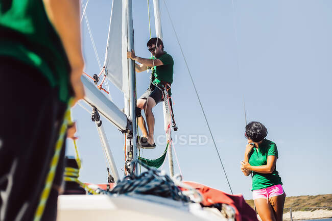 Man on rope on sail boat, woman watching — Stock Photo