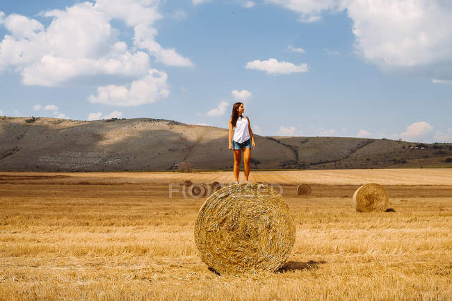 Woman standing on top of hay bale — Stock Photo