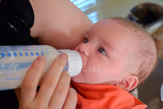 Mulher alimentando bebê menino garrafa de leite — Fotografia de Stock