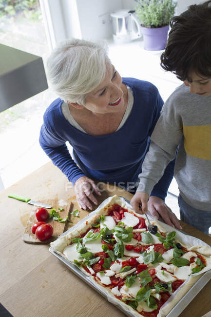 Grandmother and grandson making pizza together — Stock Photo