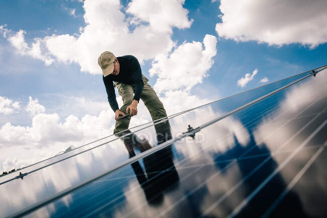 Workman installing solar panels on roof of house, low angle view — Stock Photo