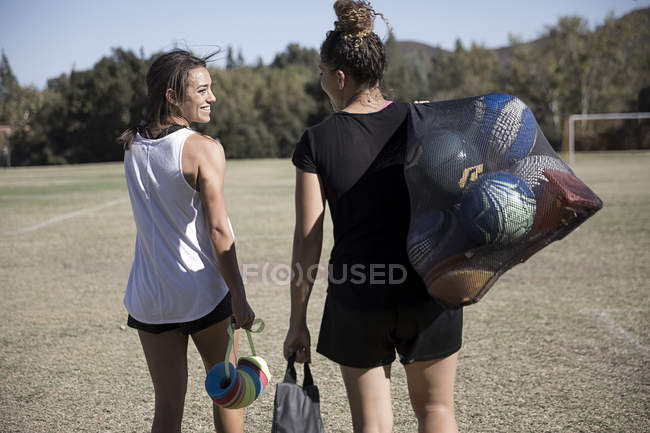 Femmes sur le terrain de football portant des ballons de football dans le sac de filet — Photo de stock