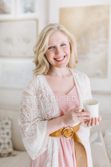 Mujer joven en sala de estar sosteniendo taza de café — Stock Photo