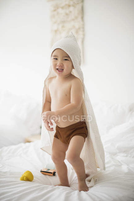 Petit garçon avec serviette à capuchon au lit — Photo de stock