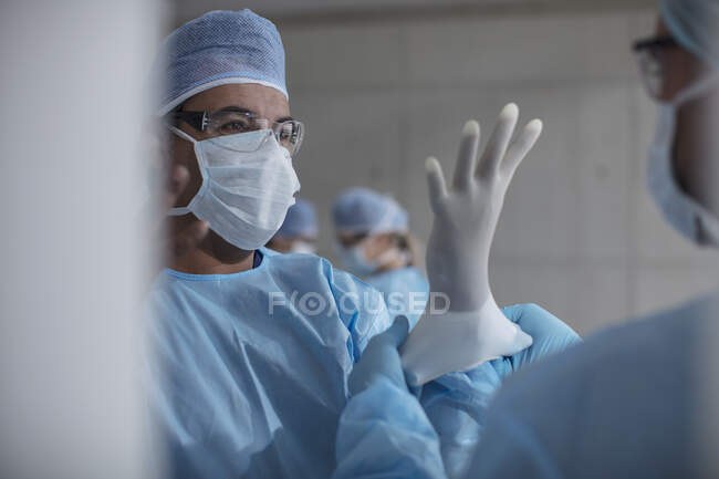 Cirujanos preparándose para la cirugía, poniéndose guantes de látex - foto de stock