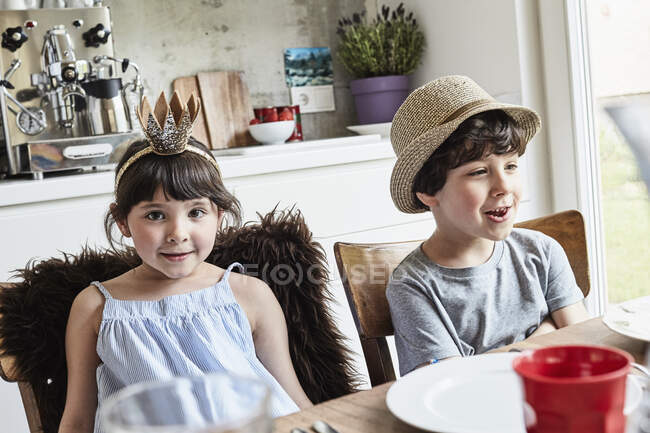 Brother and sister sitting at dinner table, smiling — Stock Photo