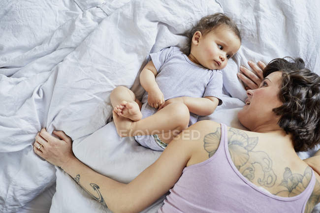 Mother and baby girl lying on bed together — Stock Photo