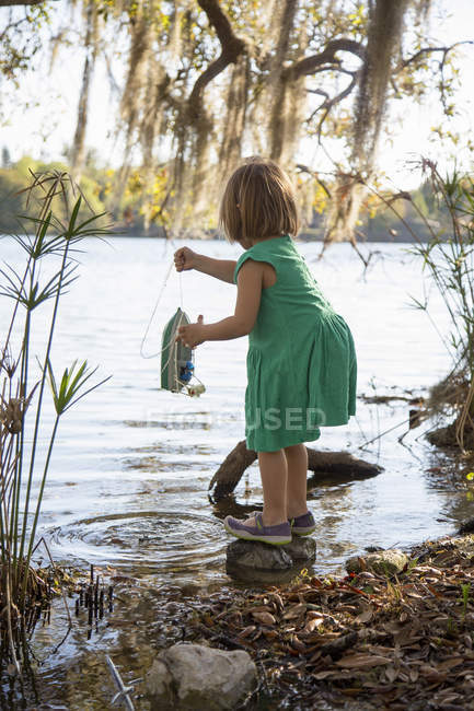 Chica jugando con juguete barco en el lago - foto de stock