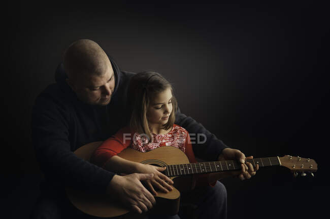 Отец учит дочь играть на гитаре — стоковое фото
