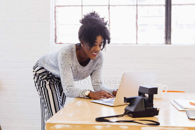 Femme dans un immeuble de bureaux industriels utilisant un ordinateur portable — Photo de stock