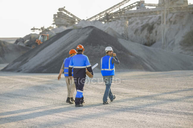 Tre lavoratori cava, a piedi attraverso cava, vista posteriore — Foto stock