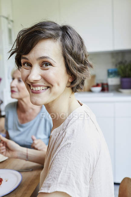 Portrait of mid adult woman at dinner table, smiling — Stock Photo