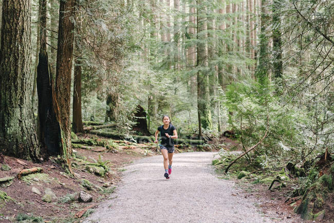 Vista frontal da mulher correndo na floresta, Vancouver, Canadá — Fotografia de Stock
