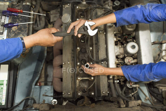 Overhead view of car mechanics hands and car engine in repair garage — Stock Photo