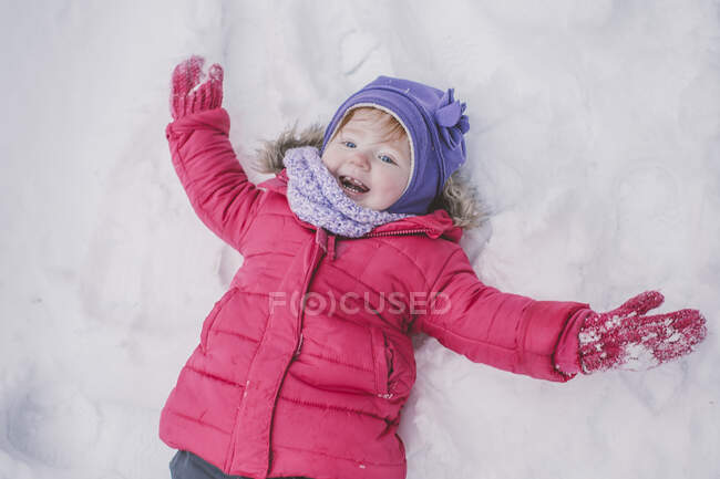 Young girl making snow angel in snow, close-up — Stock Photo