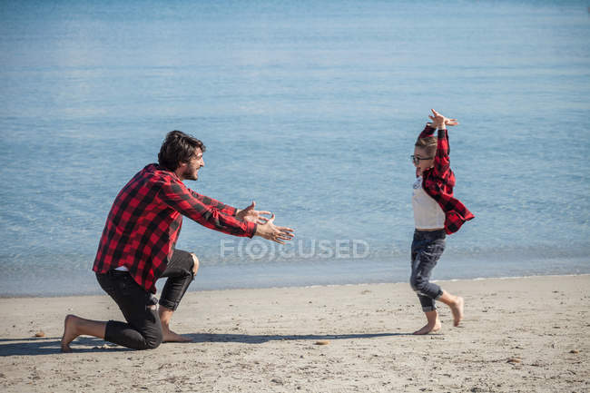 Син біжить до батька на пляжі — стокове фото