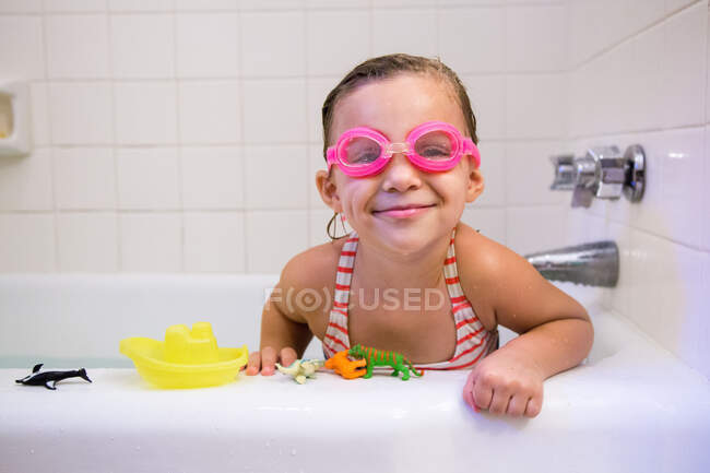 Retrato de niña con gafas de baño en el baño, mirando a la cámara sonriendo - foto de stock