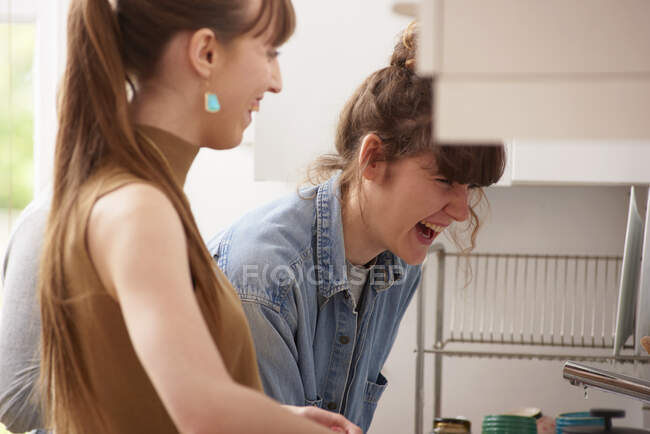 Amigos riendo en la cocina - foto de stock